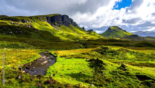Lush green valley nestled amongst dramatic, rocky mountains.  A winding stream cuts through the vibrant landscape, under a partly cloudy sky