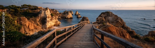 Panoramic view of a wooden boardwalk leading to the top of Algarve cliffs in Portugal, overlooking the ocean at sunset with rugged rocks, warm sunlight, and serene atmosphere, captured in high resolut