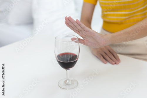 Fotografie Close up of woman hand refusing glass of red wine at home