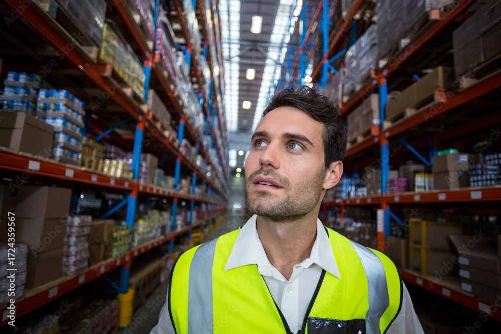 Naklejka premium Metal shelving racks filling warehouse aisle and supporting stacked cardboard boxes and pallets