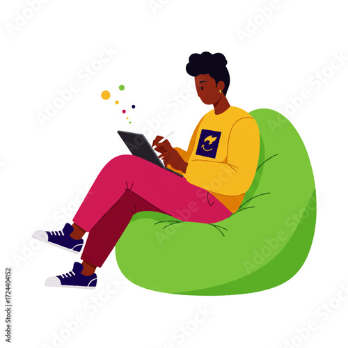 An African American man sits in a green beanbag chair, drawing on a tablet with a stylus.