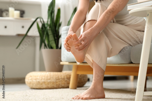 Foto Young woman with flat feet doing massage on sofa at home, closeup