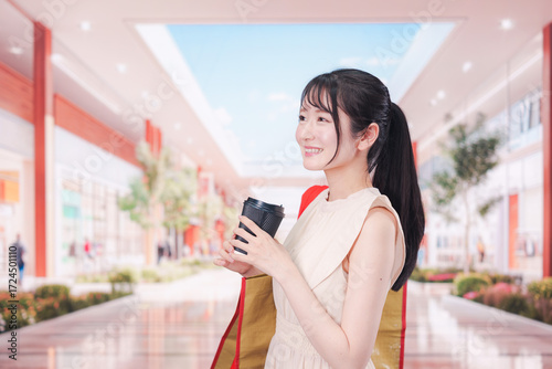 コーヒーを飲みながらショッピングモールで買い物をする女性