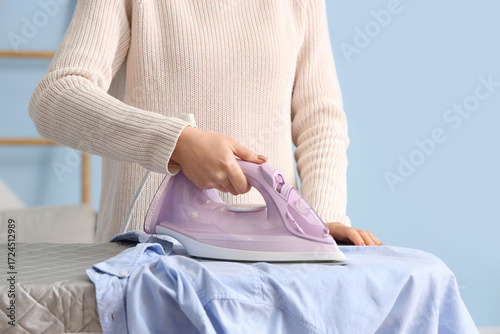 Young woman ironing blue sh...