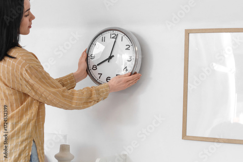Young woman hanging clock o...