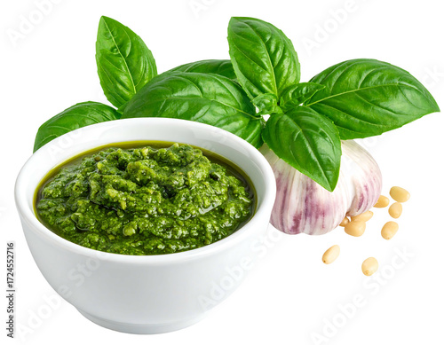 Fresh pesto in a white bowl, surrounded by basil leaves, garlic, and pine nuts