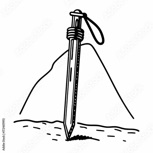 Tent stake embedded in ground with mountains in background  