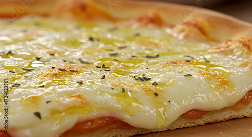 A close-up capture showcases a freshly baked pizza featuring a generous layer of melted mozzarella cheese drizzled with olive oil and sprinkled with herbs, creating an appealing and appetizing image.