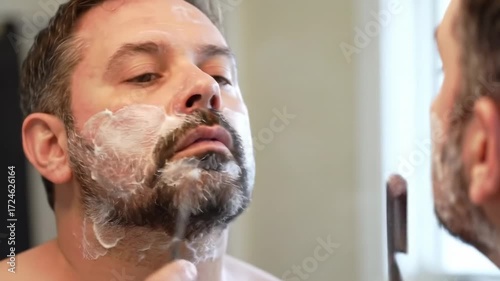 Man shaving in bathroom mirror