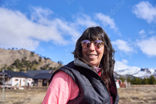 Portrait of a woman smiling at the camera, wearing sunglasses, on a sunny winter morning in the tourist town of Caviahue, in Argentine Patagonia.