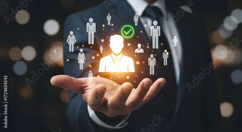 A person in a suit holding glowing human icons with a checkmark above one in their open hand