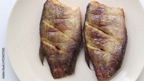 Top view of Fried gourami in a plate on a white background. Thai people often use it to make delicious sun dried fish dishes.
