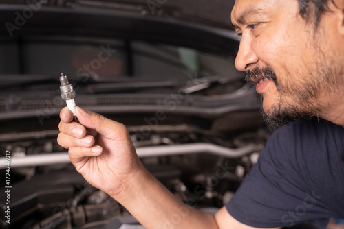 Wallpaper Mural A middle-aged Asian mechanic works under the hood of a car. Torontodigital.ca