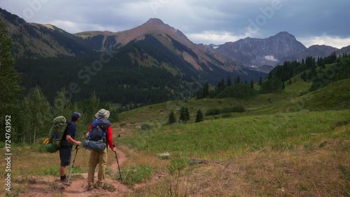 Friends backpacking camping hiker hiking trail enjoying landscape view of Capitol Peak 14er wilderness trailhead Colorado cloudy afternoon grey skies summer Rocky Mountains Elk Range Aspen Trees