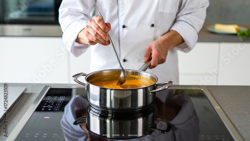 A person stirring a pot on a sleek induction cooktop