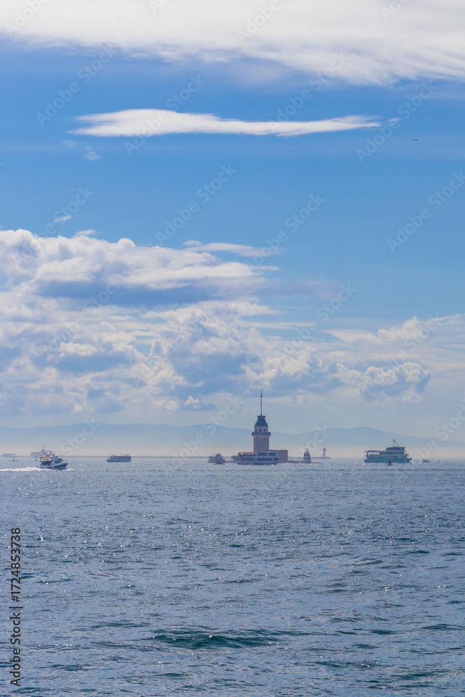 Fototapeta premium Istanbul, Turkey - March 31, 2025:The famous Maidens Tower in Istanbul with the Bosphorus in the background, surrounded by sea waves, boats and cloudy skies. A symbol of the city and a popular tourist