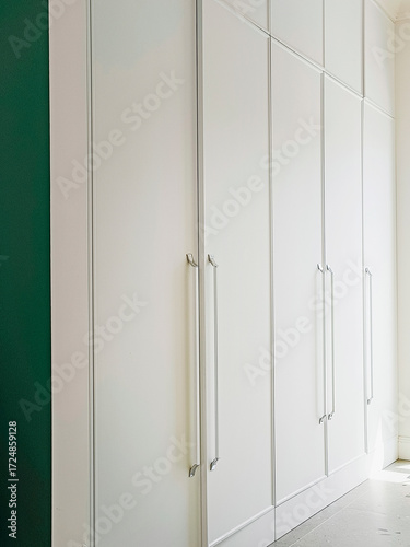 Built-in wardrobes with white doors. A detail of a modern interior.