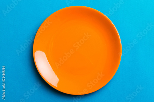 Top view of isolated of colored background empty round orange plate for food. Empty dish with space for your design