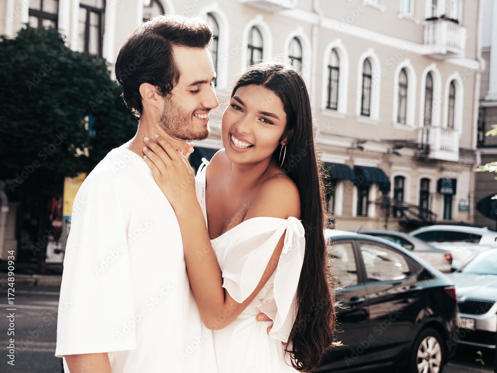 Naklejka premium Smiling beautiful woman and her handsome boyfriend. Happy cheerful family. Sexy couple posing in the street at sunrise. During romantic date at sunny summer day outdoors. Looking at each other