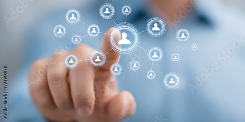 Index finger interacting with person icons in a connected network, blurred background. Light-blue shirt sleeve visible