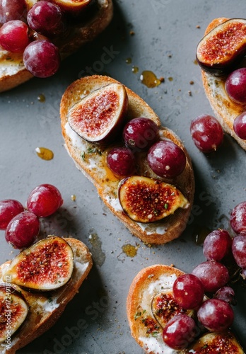 Artisan open-faced sandwiches with figs, grapes, and cheese are drizzled with honey, arranged artfully on a flat, textured surface