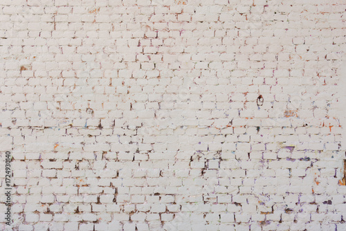 White brick wall with peeling paint and signs of aging. Urban texture with hints of graffiti and visual wear.