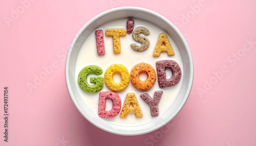 Bowl of milk with colorful cereal letters spelling “IT’S A GOOD DAY” on pink background—evokes crafted optimism, symbolic morning joy, and the rhythm of breakfast, positivity, and playful affirmation.