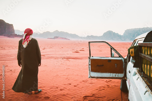 Canvas Print Bedouin man in traditional keffiyeh standing beside an open 4x4 pickup door, loo