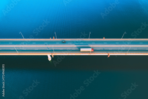 Canvastavla Aerial drone view of bridge asphalt road with cars and cargo trucks driving over blue river or lake water