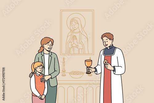 Mom brought daughter to church to talk with priest standing near altar with candles and portrait of Virgin Mary. Priest hands cup of wine to happy woman with child during saturday service.