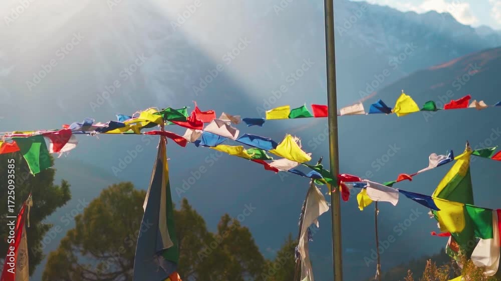 Slow motion shot of Buddhist prayer flags waving in the wind in front of snowy Himalayas with sunrays during the sunset as seen from Tayul monastery near Keylong in Lahaul, Himachal Pradesh, India.