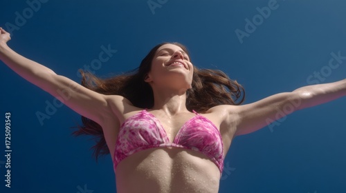 Smiling Caucasian woman basks under azure skies, embracing sun-kissed freedom, evoking midsummer celebrations and Solstice jubilance