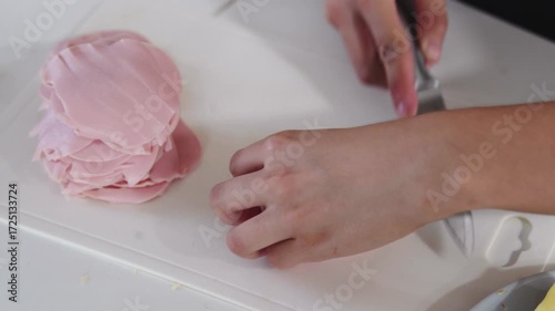 A young woman prepares fresh sandwiches with butter, sausage, and cheese on crispy bread. Close-up shots showcase the appetizing food preparation process in a modern kitchen