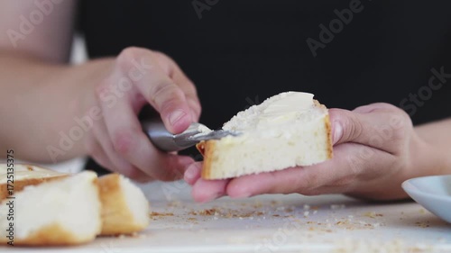 A young woman prepares fresh sandwiches with butter, sausage, and cheese on crispy bread. Close-up shots showcase the appetizing food preparation process in a modern kitchen