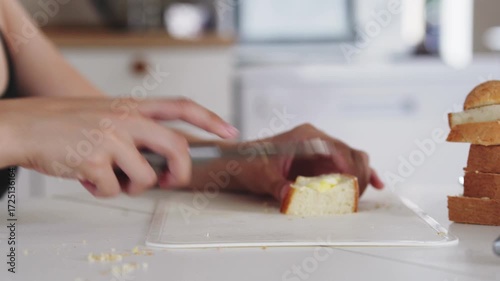 A young woman prepares fresh sandwiches with butter, sausage, and cheese on crispy bread. Close-up shots showcase the appetizing food preparation process in a modern kitchen