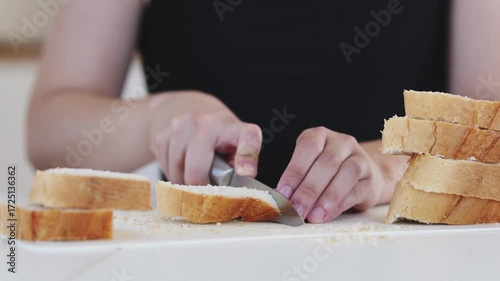 A young woman prepares fresh sandwiches with butter, sausage, and cheese on crispy bread. Close-up shots showcase the appetizing food preparation process in a modern kitchen