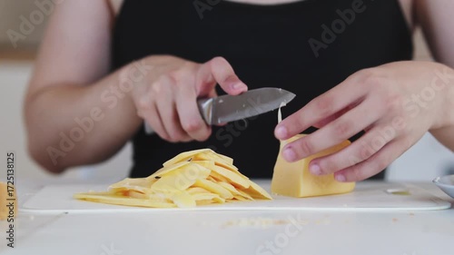 A young woman prepares fresh sandwiches with butter, sausage, and cheese on crispy bread. Close-up shots showcase the appetizing food preparation process in a modern kitchen