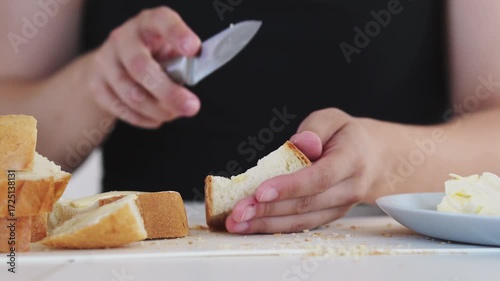 A woman prepares delicious sandwiches with cheese, butter, and sausage in a sunny kitchen. Authentic cooking process showcasing simple, comforting food preparation