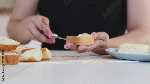 A woman prepares delicious sandwiches with cheese, butter, and sausage in a sunny kitchen. Authentic cooking process showcasing simple, comforting food preparation