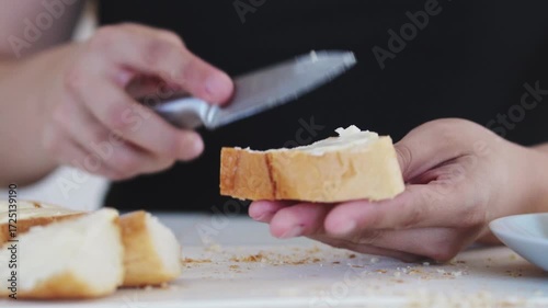 A woman prepares delicious sandwiches with cheese, butter, and sausage in a sunny kitchen. Authentic cooking process showcasing simple, comforting food preparation