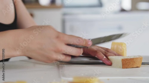 A woman prepares delicious sandwiches with cheese, butter, and sausage in a sunny kitchen. Authentic cooking process showcasing simple, comforting food preparation