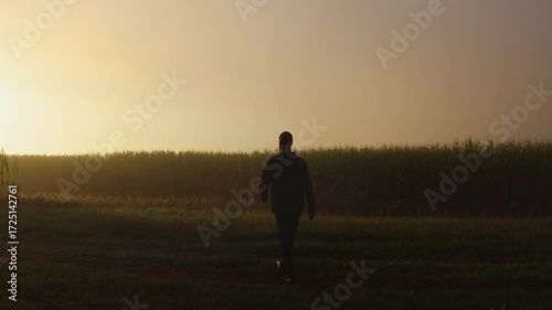 Man, farmer in wellingtons shoe walking to corn field with misty fog during sunrise. Czech agriculture landscape background