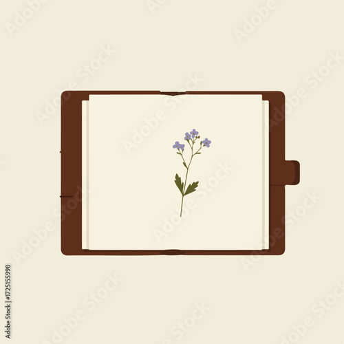 A purple flower pressed inside of an open, brown leather notebook