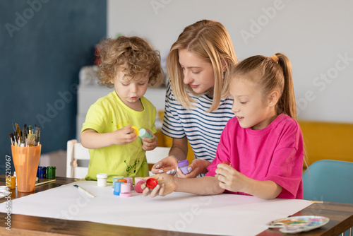 Happy family painting together. Young mother learn her little children to draw. Family art therapy and having fun time at home.