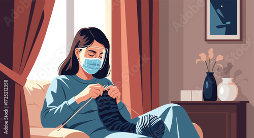A woman wearing a face mask is knitting a sock while sitting on a couch at home.