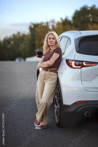 A beautiful woman stands next to her car