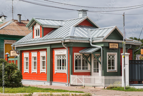 Foto A red-and-green wooden Russian house with white windows