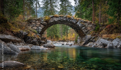 A serene stone arch bridge spans a clear mountain stream, surrounded by autumn foliage and lush greenery.