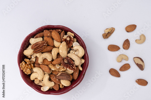 Assorted mixed nuts in red bowl on white—healthy snack, vegan protein, natural food concept. Top view.
