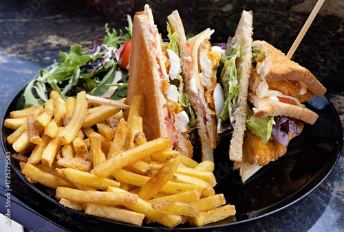 Sandwich toast with ketchup, mayonnaise and french fries arranged on a plate